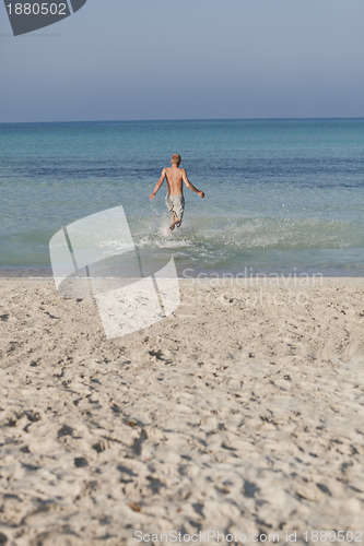 Image of man running on the beach in water portrait