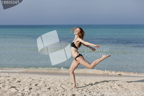 Image of Woman with bikini jumping happily on the beach landscape