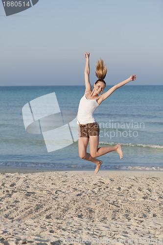 Image of Cheerful woman jumping laughing at beach portrait