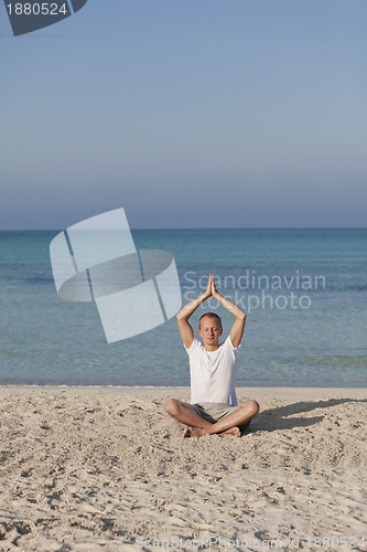 Image of Man makes yoga sports on the beach portrait