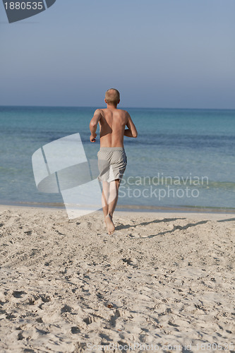 Image of man running on the beach in water portrait