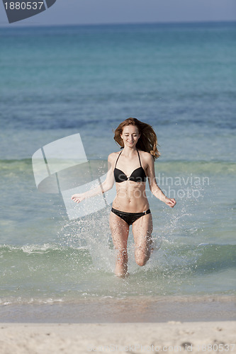Image of Woman with bikini in the sea jumping portrait