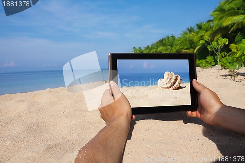 Image of hands holding tablet pc on beach