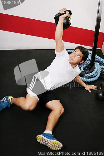 Image of Young man doing kettlebell workout on gym