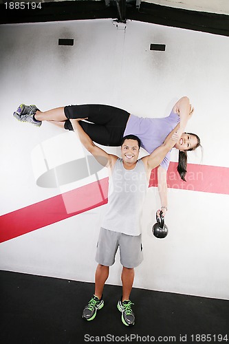 Image of Handsome man lifting a beautiful woman at the gym 