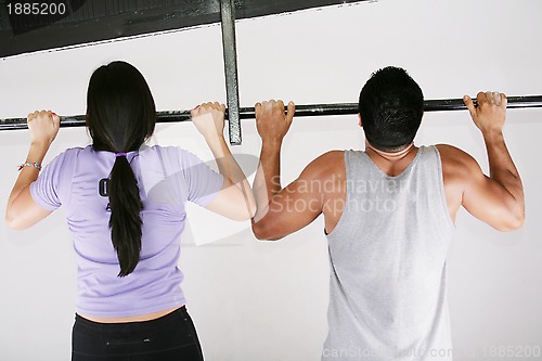 Image of Young adult fitness woman and man preparing to do pull ups in pu