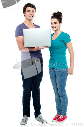 Image of Teen friends holding laptop. Full length shot