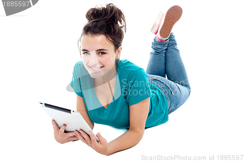 Image of Causal teenager lying on floor holding new tablet pc