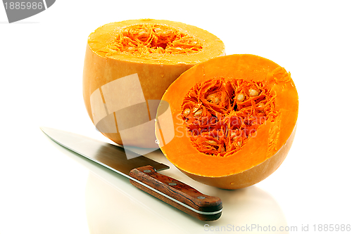 Image of Two halves of a ripe pumpkin and a table knife.