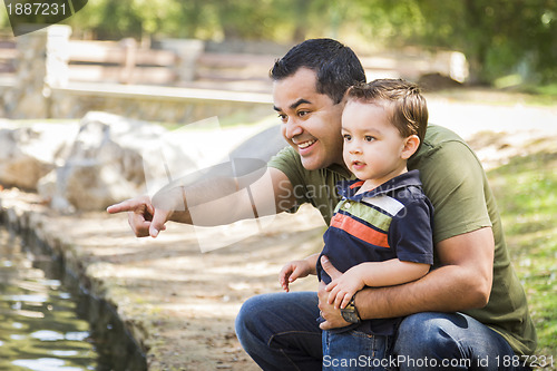 Image of Hispanic Father Points with Mixed Race Son at the Park