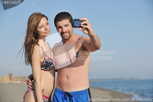 Image of happy young couple in love taking photos on beach