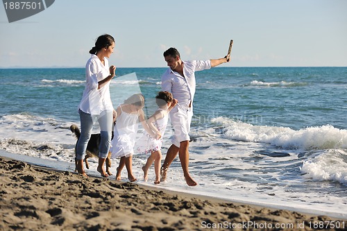 Image of happy family playing with dog on beach