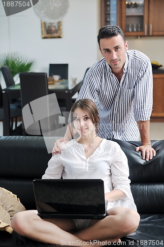 Image of joyful couple relax and work on laptop computer at modern home