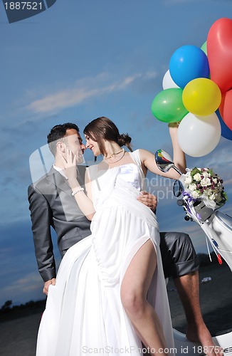 Image of just married couple on the beach ride white scooter