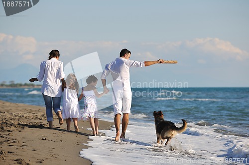 Image of happy family playing with dog on beach