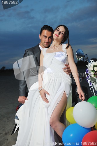 Image of just married couple on the beach ride white scooter