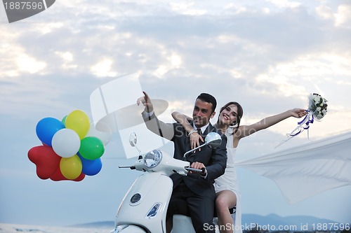 Image of just married couple on the beach ride white scooter