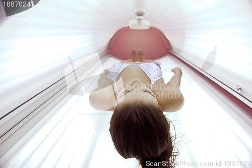 Image of Beautiful young woman tanning in solarium