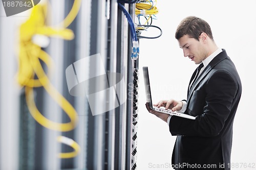 Image of businessman with laptop in network server room