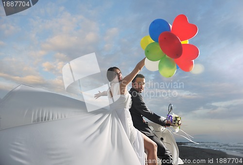 Image of just married couple on the beach ride white scooter