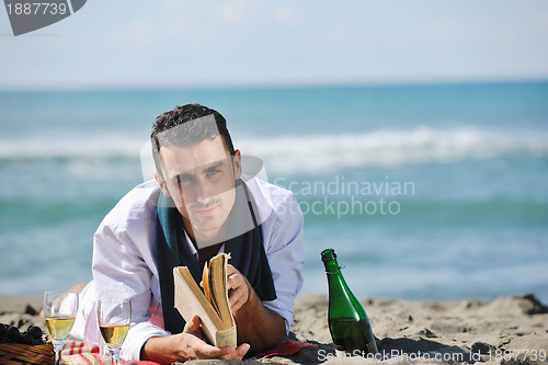 Image of man reading book at beach