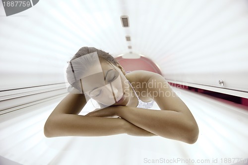 Image of Beautiful young woman tanning in solarium