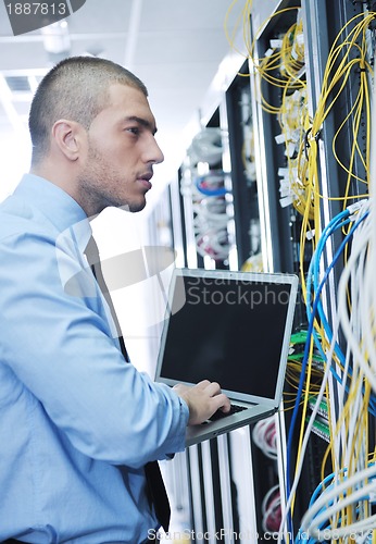 Image of businessman with laptop in network server room