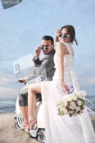 Image of just married couple on the beach ride white scooter