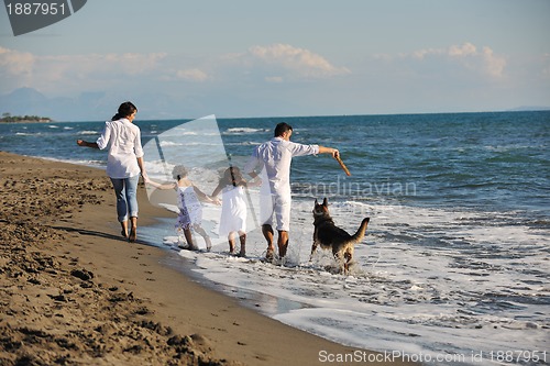 Image of happy family playing with dog on beach