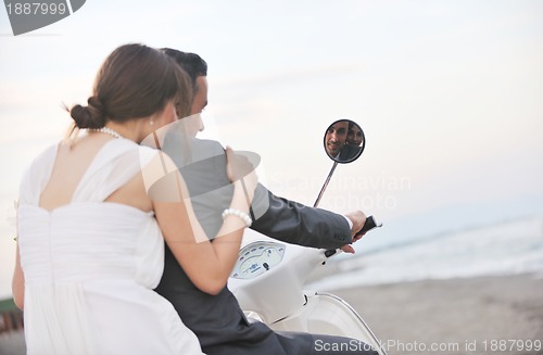 Image of just married couple on the beach ride white scooter