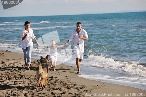 Image of happy family playing with dog on beach