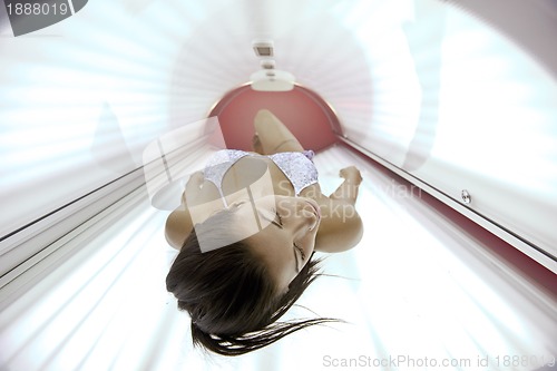 Image of Beautiful young woman tanning in solarium