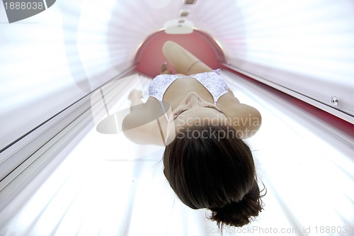 Image of Beautiful young woman tanning in solarium