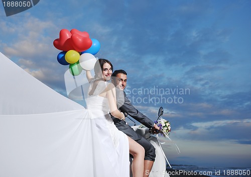 Image of just married couple on the beach ride white scooter