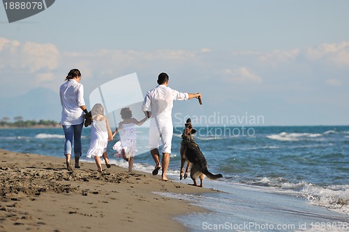 Image of happy family playing with dog on beach