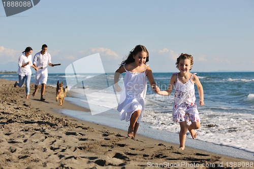 Image of happy family playing with dog on beach