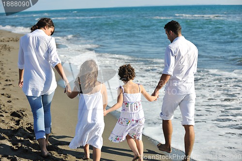 Image of happy family playing with dog on beach