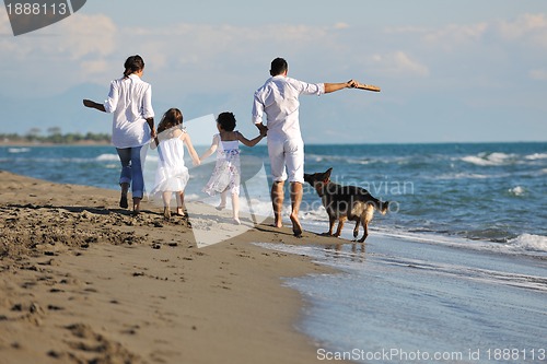 Image of happy family playing with dog on beach