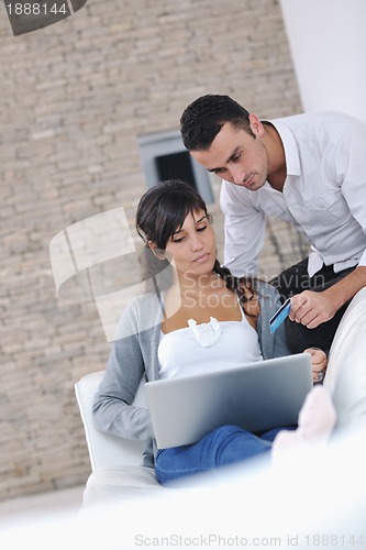 Image of joyful couple relax and work on laptop computer at modern home