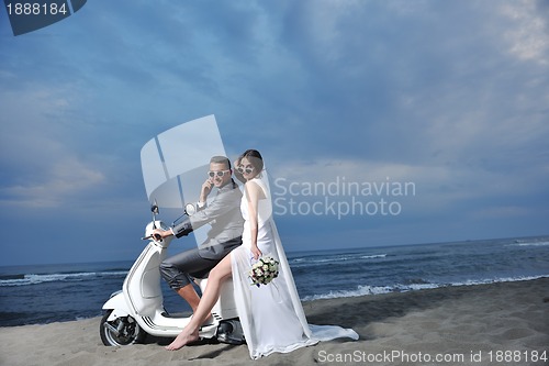Image of just married couple on the beach ride white scooter