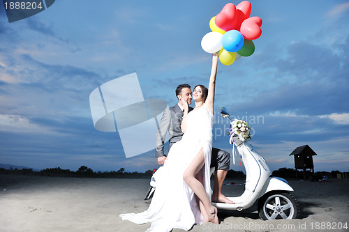 Image of just married couple on the beach ride white scooter