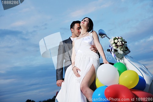 Image of just married couple on the beach ride white scooter