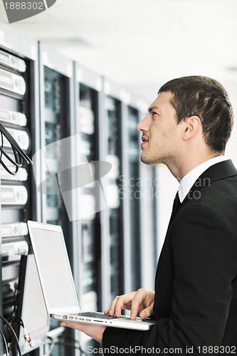 Image of businessman with laptop in network server room