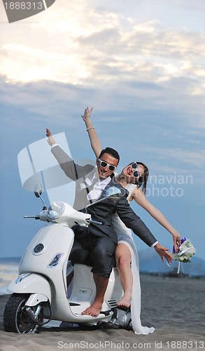 Image of just married couple on the beach ride white scooter