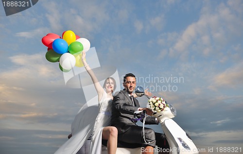 Image of just married couple on the beach ride white scooter