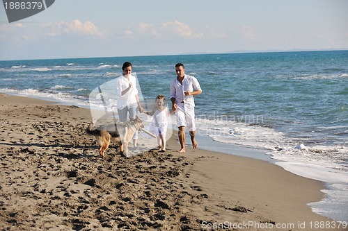 Image of happy family playing with dog on beach