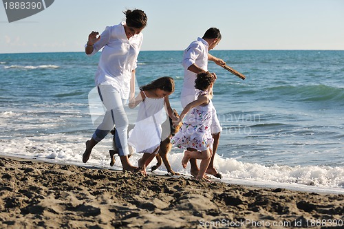 Image of happy family playing with dog on beach