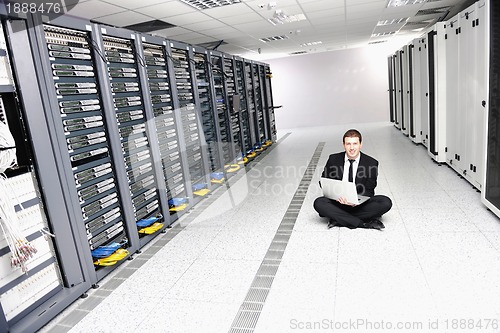 Image of businessman with laptop in network server room