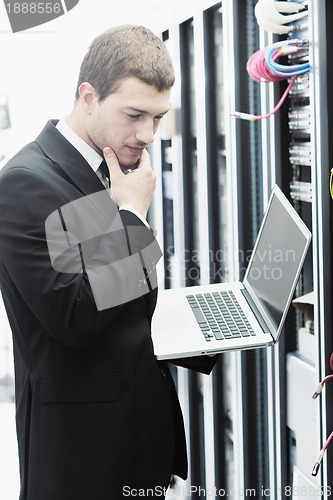 Image of businessman with laptop in network server room