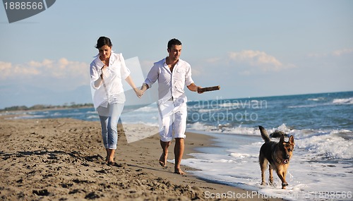 Image of happy family playing with dog on beach